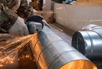 a worker cuts a pipe with an angle grinder