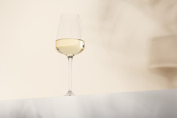 A glass of white wine is on the table. Light background.