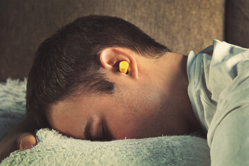 Daytime sleep. rest, Siesta. Yellow ear plugs in the ears of a young boy sleeping in the afternoon...