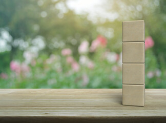 Four wood block cubes on wooden table over blur pink flower and tree in park