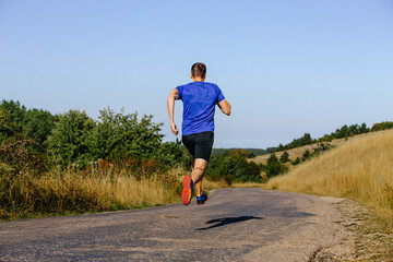 back male runner running on road on plain