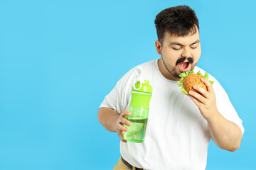 Concept of weight problems, young fat man on blue background