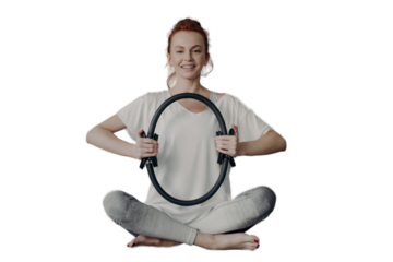 Cheerful fitness woman in active wear sitting in lotus position and exercising with pilates ring