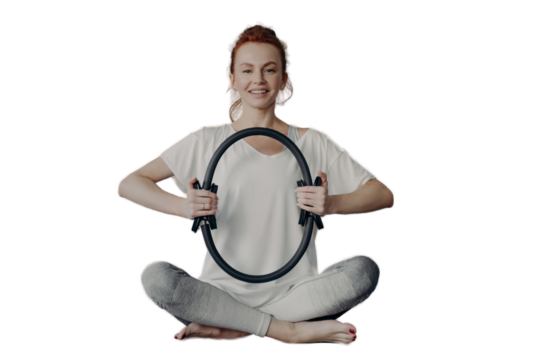 Cheerful fitness woman in active wear sitting in lotus position and exercising with pilates ring