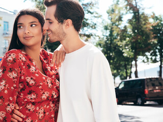 Obraz premium Smiling beautiful woman and her handsome boyfriend. Happy cheerful family. Sexy couple posing in the street at sunrise. During romantic date at sunny summer day outdoors. Looking at each other