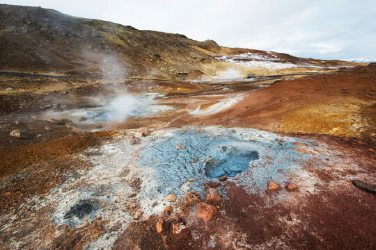 A geothermal pool steams amongst an explosion of earthen colors in Iceland.
