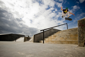 A young skateboarder, kickflips his skateboard over a 7-stair gap at the skatpark in Whitefish, Montana.