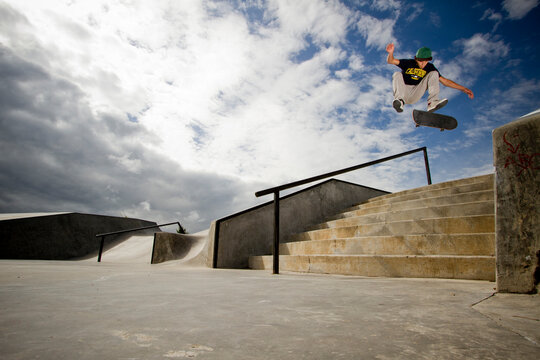 A young skateboarder, kickflips his skateboard over a 7-stair gap at the skatpark in Whitefish, Montana.