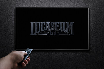 Obraz premium TV screen playing Lucasfilm movie. Man turns on TV with remote control. Moscow, Russia - January 18, 2023.