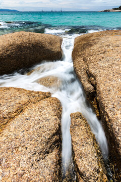 Water rushes between rocks at a Bicheno beach in Tasmania.