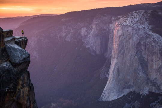 Man standing on the edge of a big cliff with Yosemite Valley in background. Taft Point, Yosemite, CA, USA.