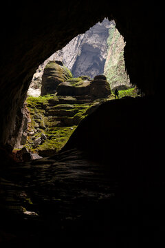 A cave explorer stands silhouetted agains the sunlight coming in through the first doline, or skylight.