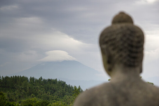 A statue of Budhha looking at Mt Merapi in the distance.