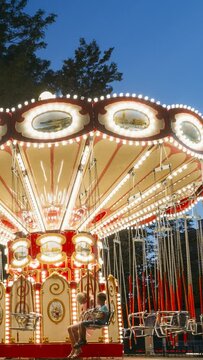 Brightly Illuminated Rotating High Speed Carousel Merry-Go-Round hyperlapse. Summer Evening In City Amusement Park vertical, vertical footage, vertical video.