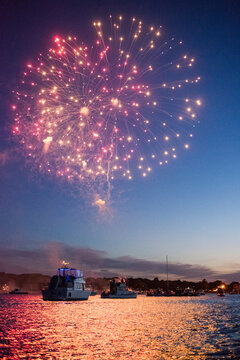Fourth of July firework display above boats in sea