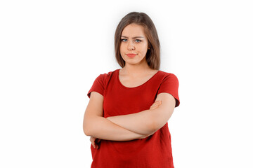 Young woman frowning face in displeasure, keeps arms folded. Attractive girl in closed posture...