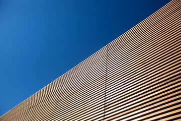 Wall of wooden slats on a sky background. Wooden floor. Wooden fence. Wooden wall. Modern architectural wall.
