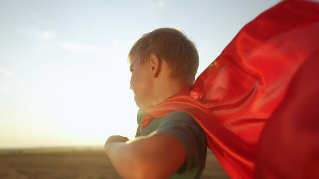 kid superhero. boy happy family a dream concept. baby boy superhero close-up in red cape at sunset. portrait child superhero close-up from lifestyle the back. strength fantasy concept