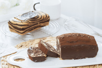 Chocolate marble loaf cake with chocolate glaze. On white cafe table.