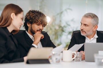 A team of entrepreneurs is studying documentation during a meeting. Business partners study the company's financial statements for the past month.