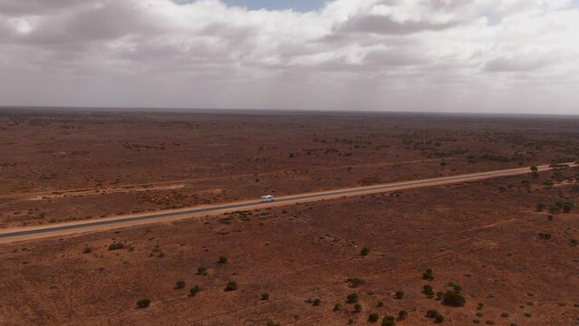 Campervan roadtripping on empty road in Australiaon a cloudy day. High drone following shot