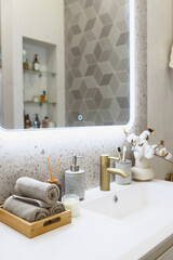 luxury modern bathroom interior with gold tap (faucet), grey stone walls, hand towels and liquid soap. Scandinavian minimalistic style.
