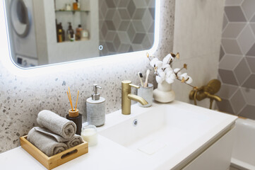 luxury modern bathroom interior with gold tap (faucet), grey stone walls, hand towels and liquid soap. Scandinavian minimalistic style.