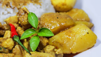 Close-up photo of Chicken curry rice in yellow spice sauce with potatoes and boiled egg served on white plate isolated on black dark background. Close up side angle Chicken curry rice.