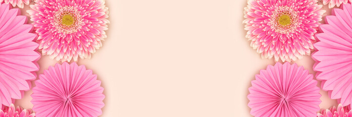 Banner with pink gerbera flowers and tissue paper fans on a beige background. Place for text.