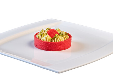 Sweet dessert: Tarts, Tartlets. A bright red basket of shortbread dough and a delicate green pistachio filling. Close-up on a white plate