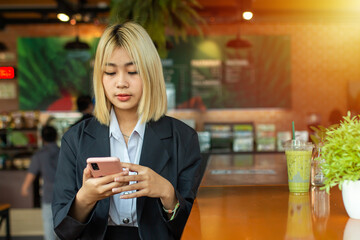 While waiting for her flight, the beautiful business girl passed the time by watching a Talk Show on her phone in cafe.