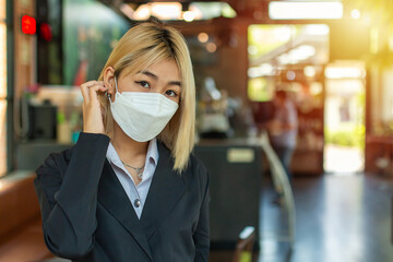 Beautiful businesswoman with golden hair staring at the camera while standing in a cafe.