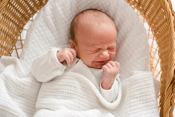 Crying baby 1-2 months old wake up in crib with stomach colic pain lying in bedtime closeup....