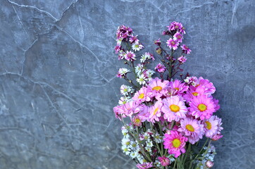 purple bouquet beside cement wall