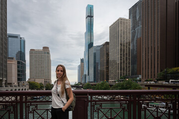 Fototapeta premium Portrait of a blonde young girl in short sleeves on a Chicago city bridge