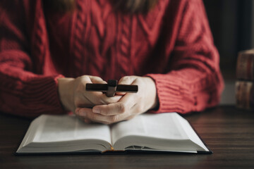 Fototapeta premium Close up of an open bible with a cross for morning devotion on a wooden table.