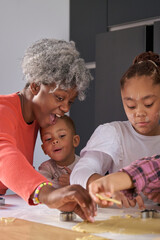 African family cutting cookie shapes in a cookie dough in the kitchen. Horizontal extended family.