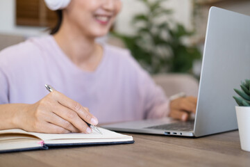 Close up hand - student wear wireless headphone study online with skype teacher, happy young woman...