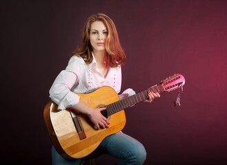 Obraz na płótnie Canvas Attractive girl, woman playing guitar in the studio.