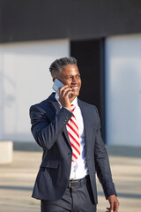 Young hispanic businessman smiling happy talking with smartphone in the city.