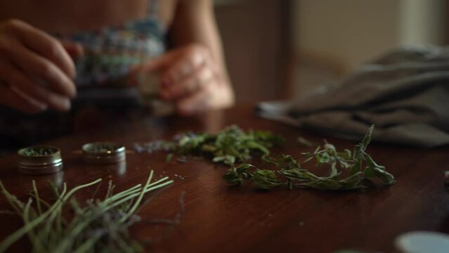 woman prepares herbs for tobacco with the help of a herb grinder to grind a cannabis.