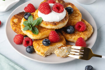 Cottage cheese pancakes with raspberries and blueberry on light background, breakfast or lunch