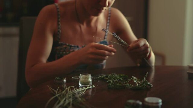 woman prepares herbs for tobacco with the help of a herb grinder to grind a cannabis.