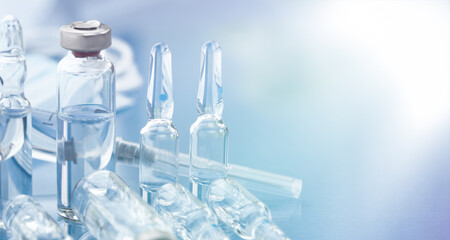 A medicine ampoule, a medical syringe, and disposable masks are close-up on a light blue background.