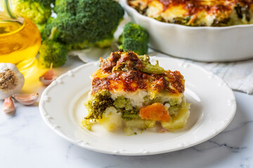Casserole Cauliflower and broccoli baked with cheese sauce in a pot close-up on a wooden table. Horizontal top view from above. Broccoli gratin.