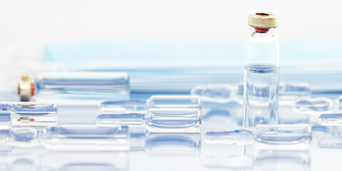 Medical ampoules for injection on a light blue background. Scattered glass ampoules with medicine on the table. Medicines and disease treatment, pharmacology and scientific concepts