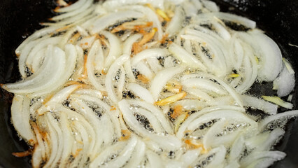 Frying sliced onion. Cooking onion on pan, close up