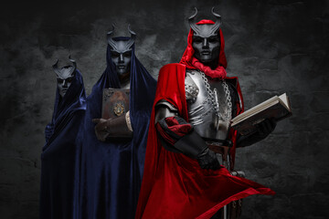 Studio shot of mysterious brotherhood of cult dressed in mantles and horned masks.