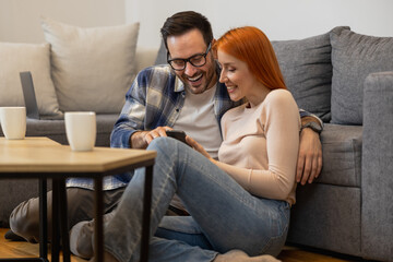 Happy young woman and man using smartphone together