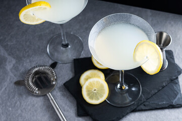 Lemon drop martini cocktail on gray stone and black background